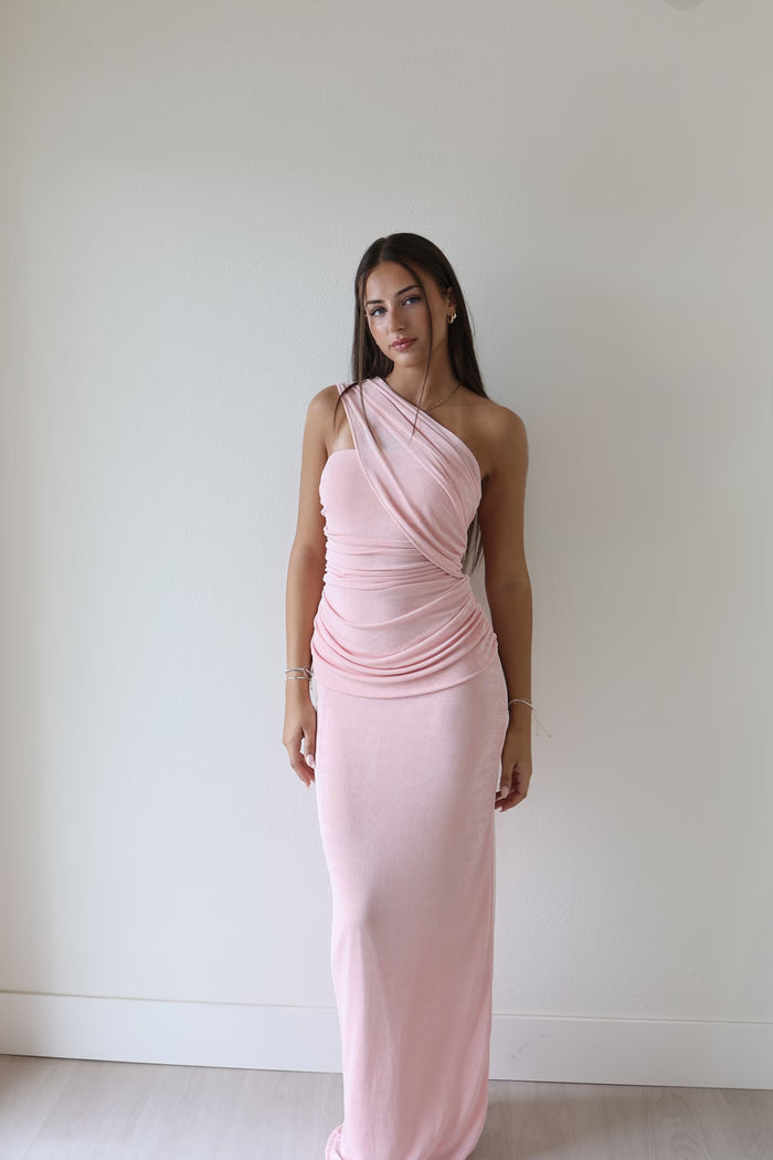 Woman wearing an elegant pink one-shoulder gown, a stylish look for a mother of the bride accessorised with fine jewellery