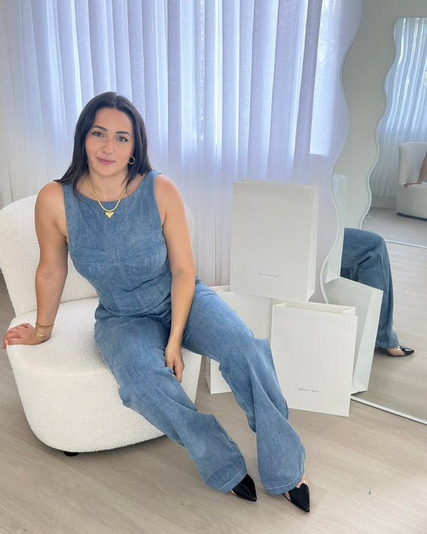 Woman wearing a matching blue denim co-ord set with sleeveless top and wide-leg jeans, seated in a bright room, styled by BELLA n' BEAR.