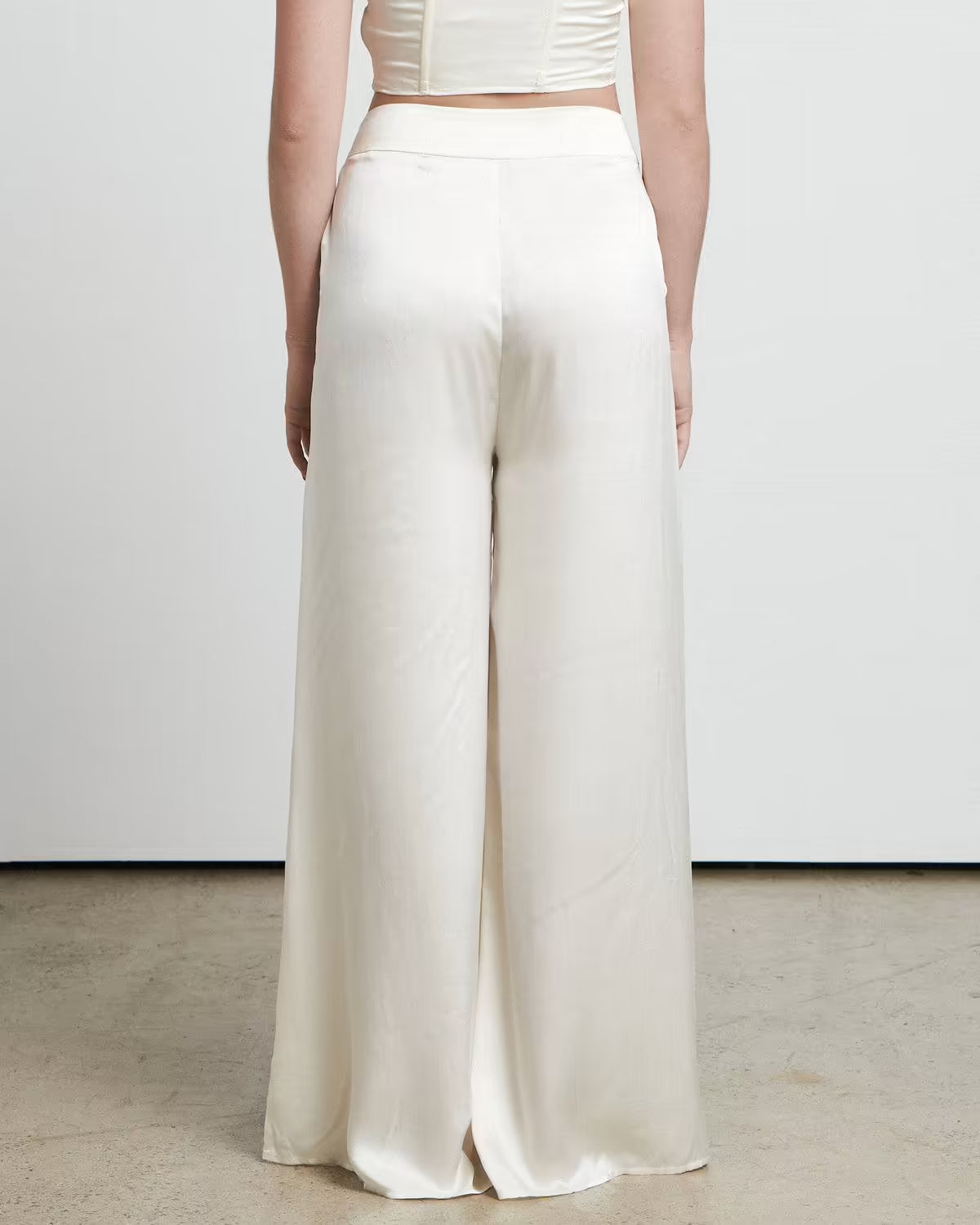 Woman wearing cream wide leg trousers styled from behind, showing the flowing silhouette from BELLA n' BEAR