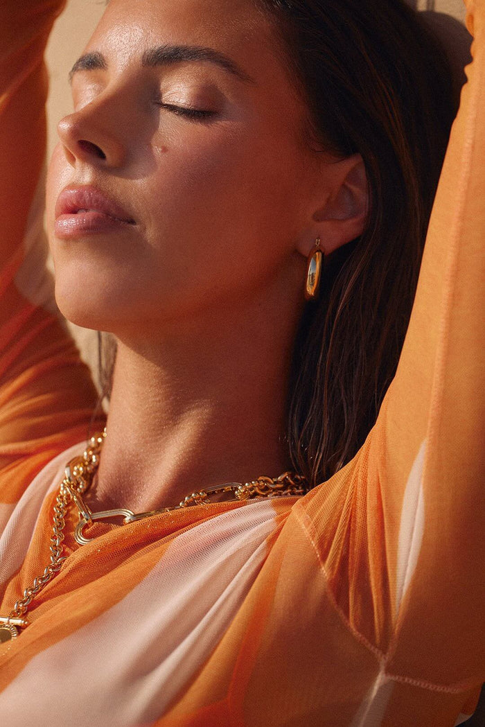 Woman wearing gold hoop earrings and layered necklaces, styled with BELLA n' BEAR fashion accessories