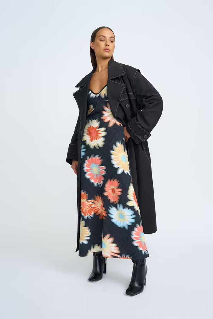 How to dress for Melbourne winter - woman in a long black coat layered over a floral dress, Melbourne street style