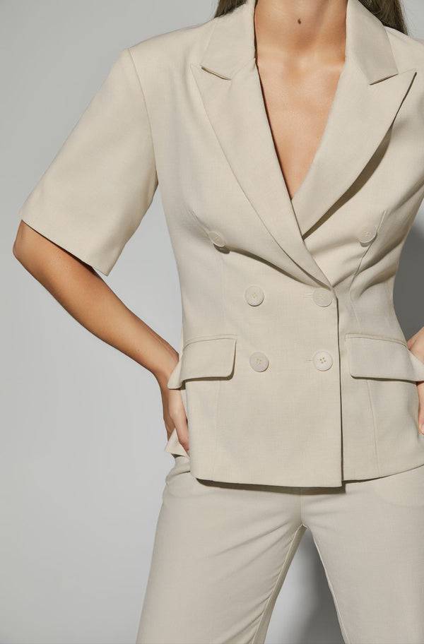 Woman wearing a light cream double-breasted blazer and matching tailored pants, a smart casual outfit idea for Australian women