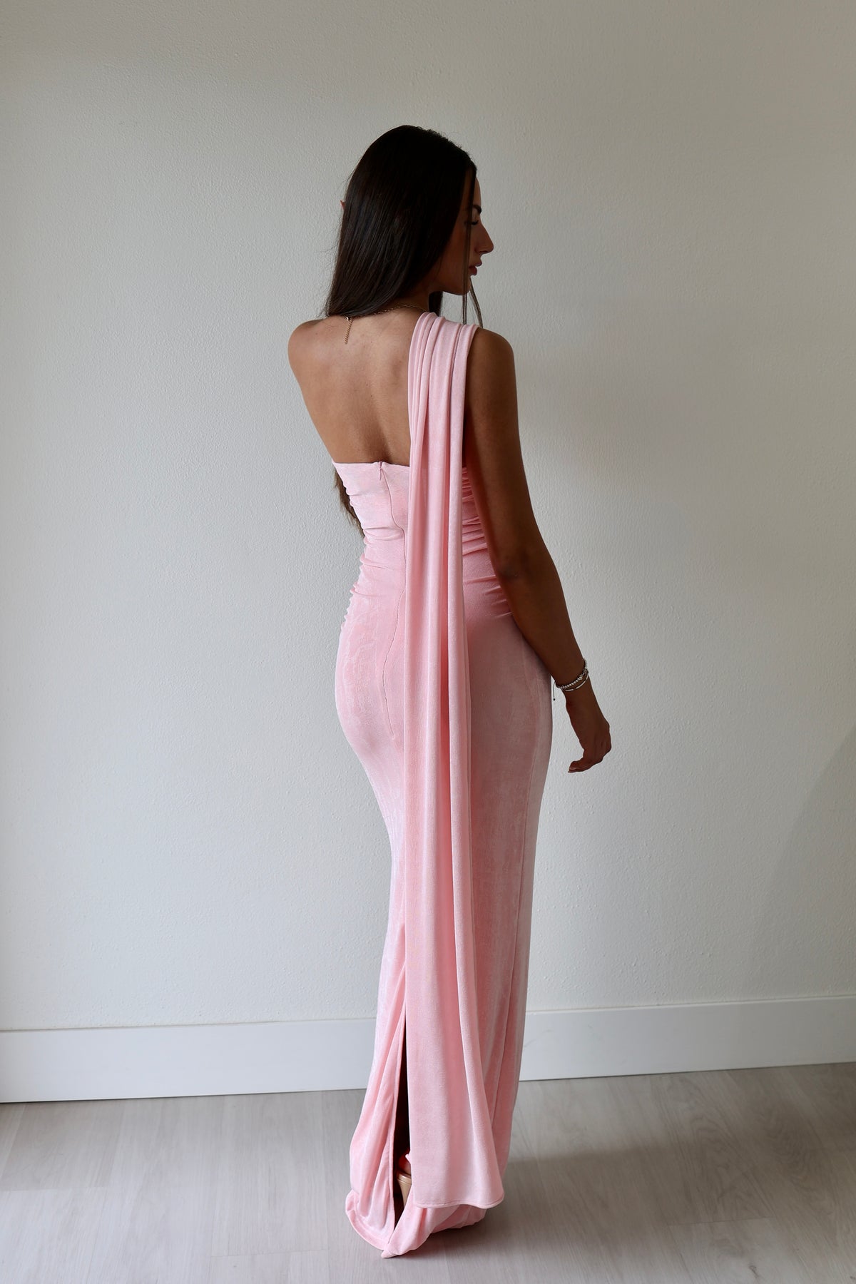 Iesha dress in soft pink, featuring a strapless design and flowing back drape, worn by a model.