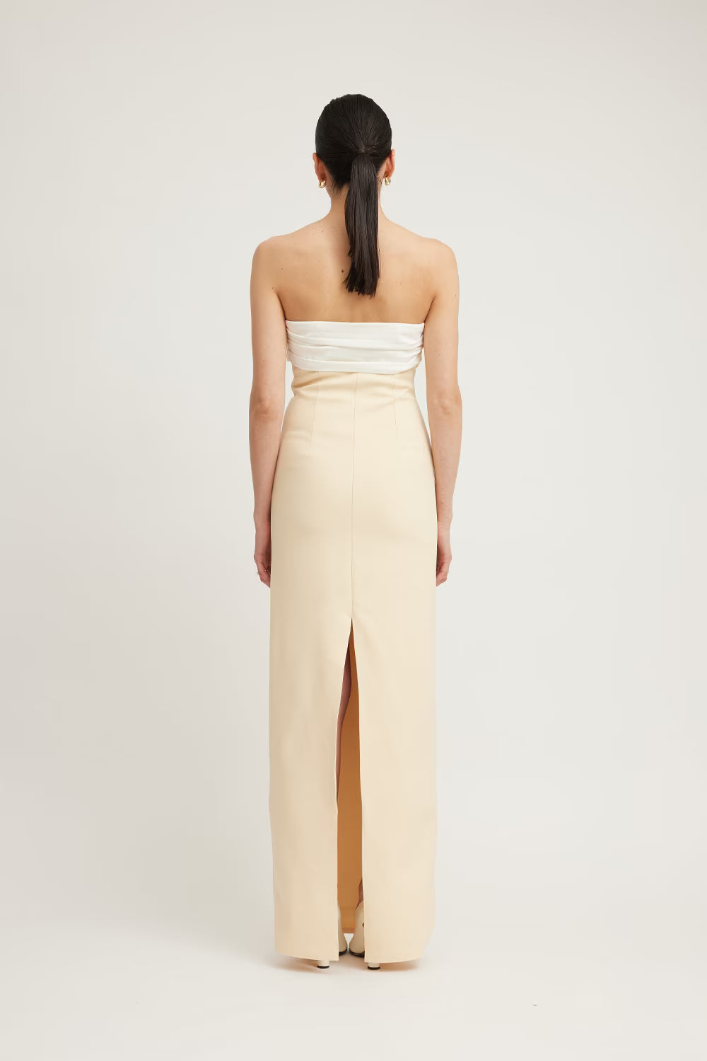 Strapless beige maxi dress with a fitted bodice and a back slit, shown from the rear view.