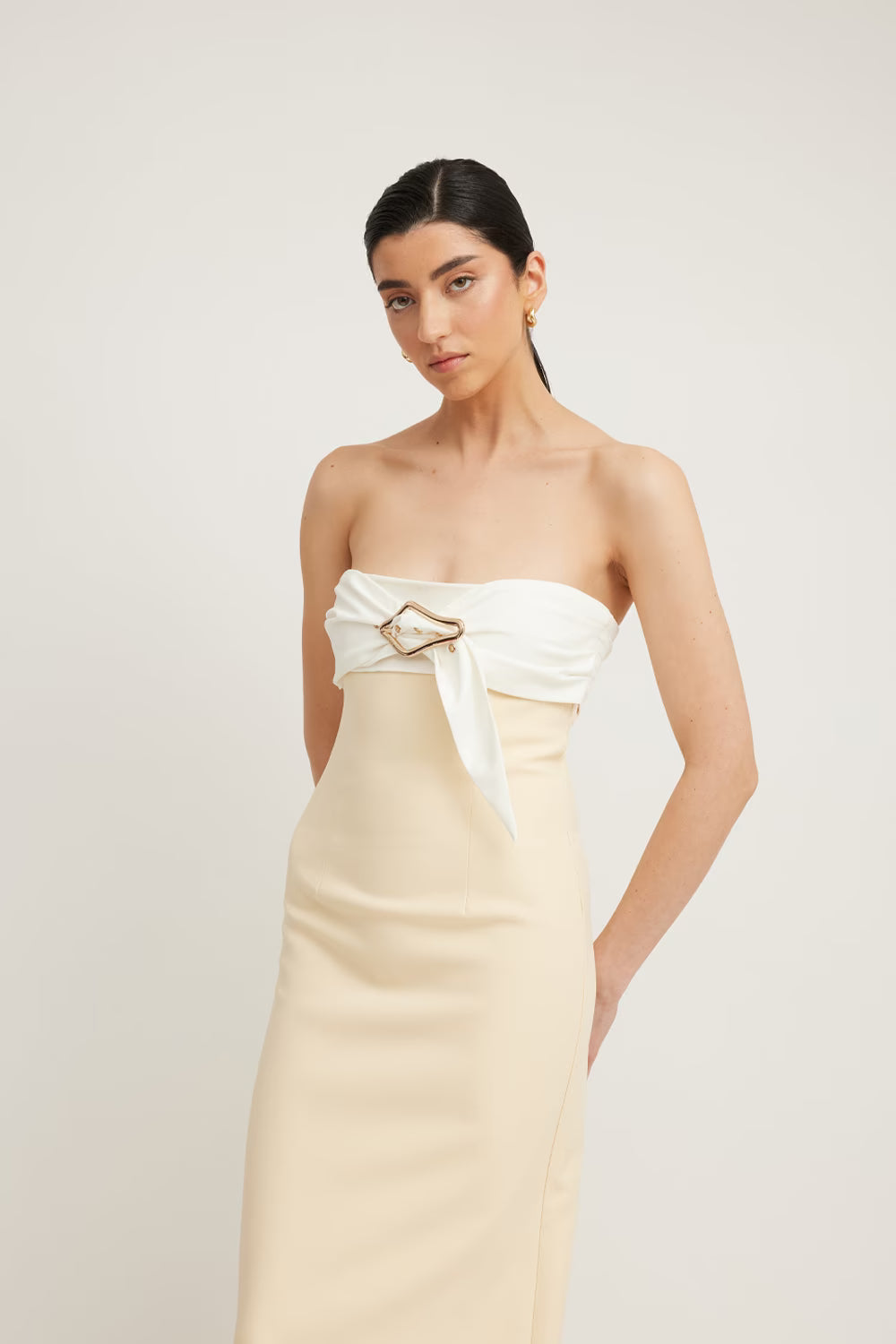 Kasai dress featuring a strapless design with a white top and beige skirt, styled with a gold buckle detail.