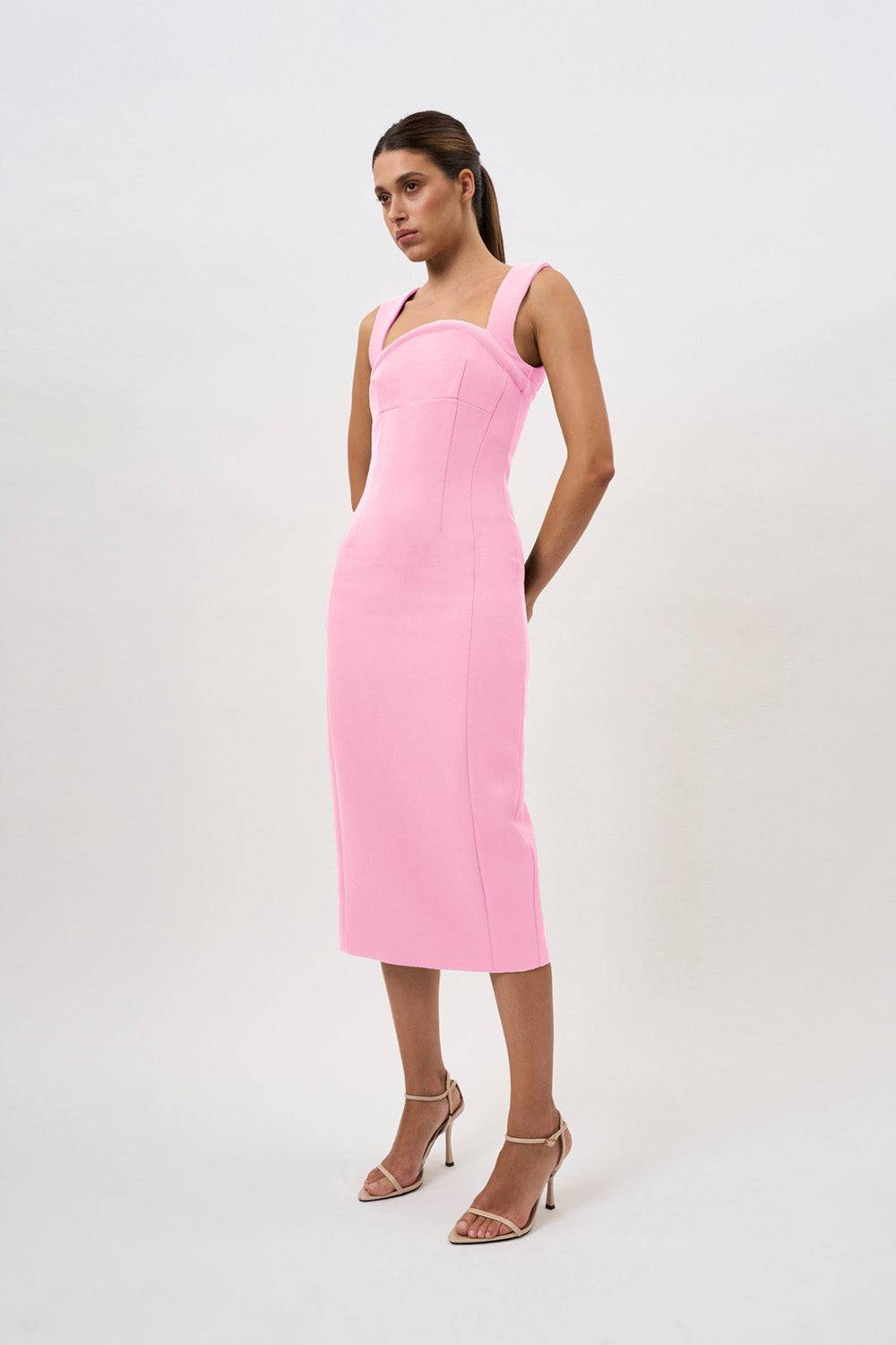 a woman is wearing a pink By Johnny Elara midi dress and heels