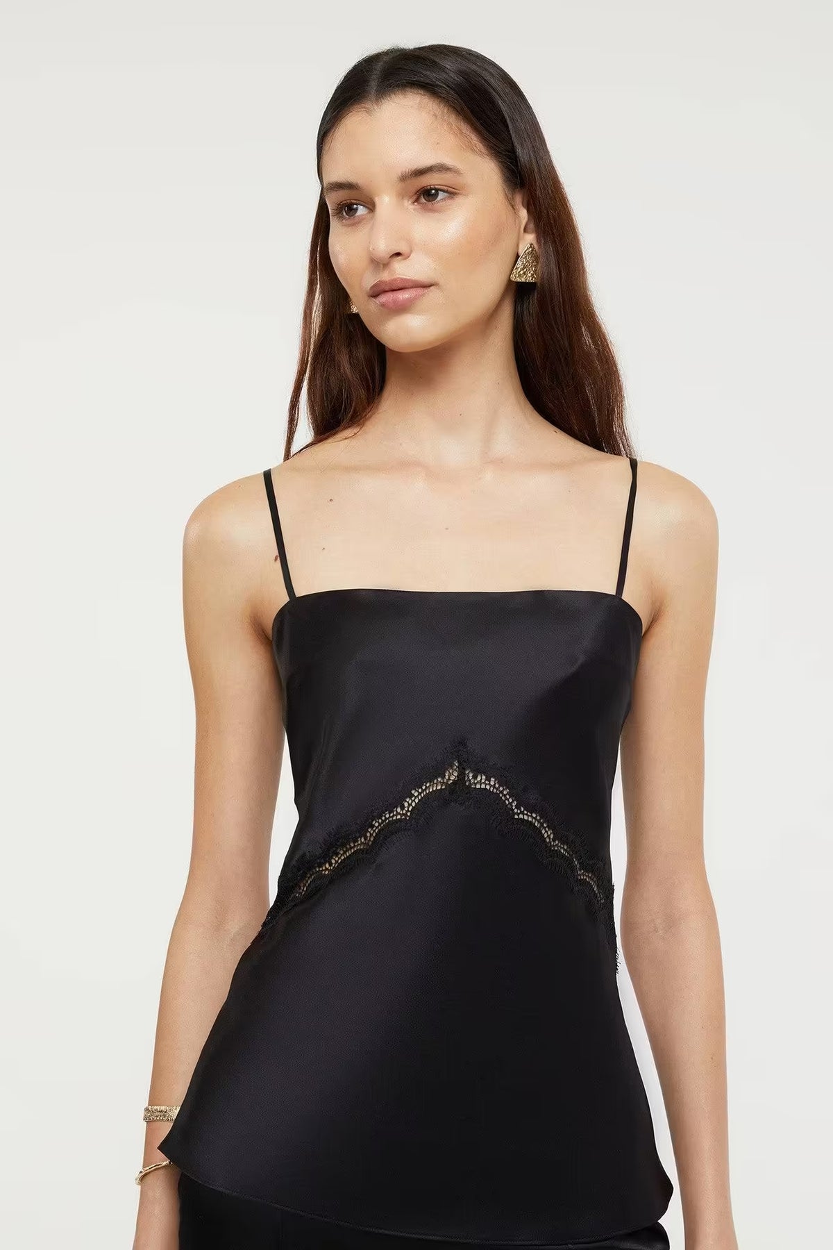 Black Nomie Cami top with thin straps and lace detailing, worn by a model against a neutral background.