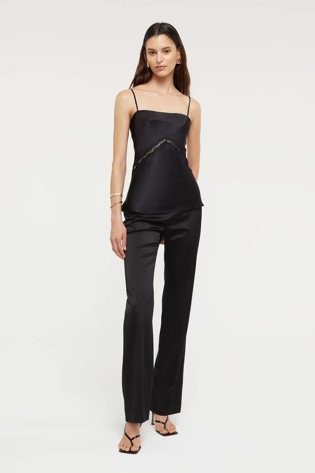 Black Nomie Cami top with thin straps, styled with black fitted pants and worn by a model against a light background.