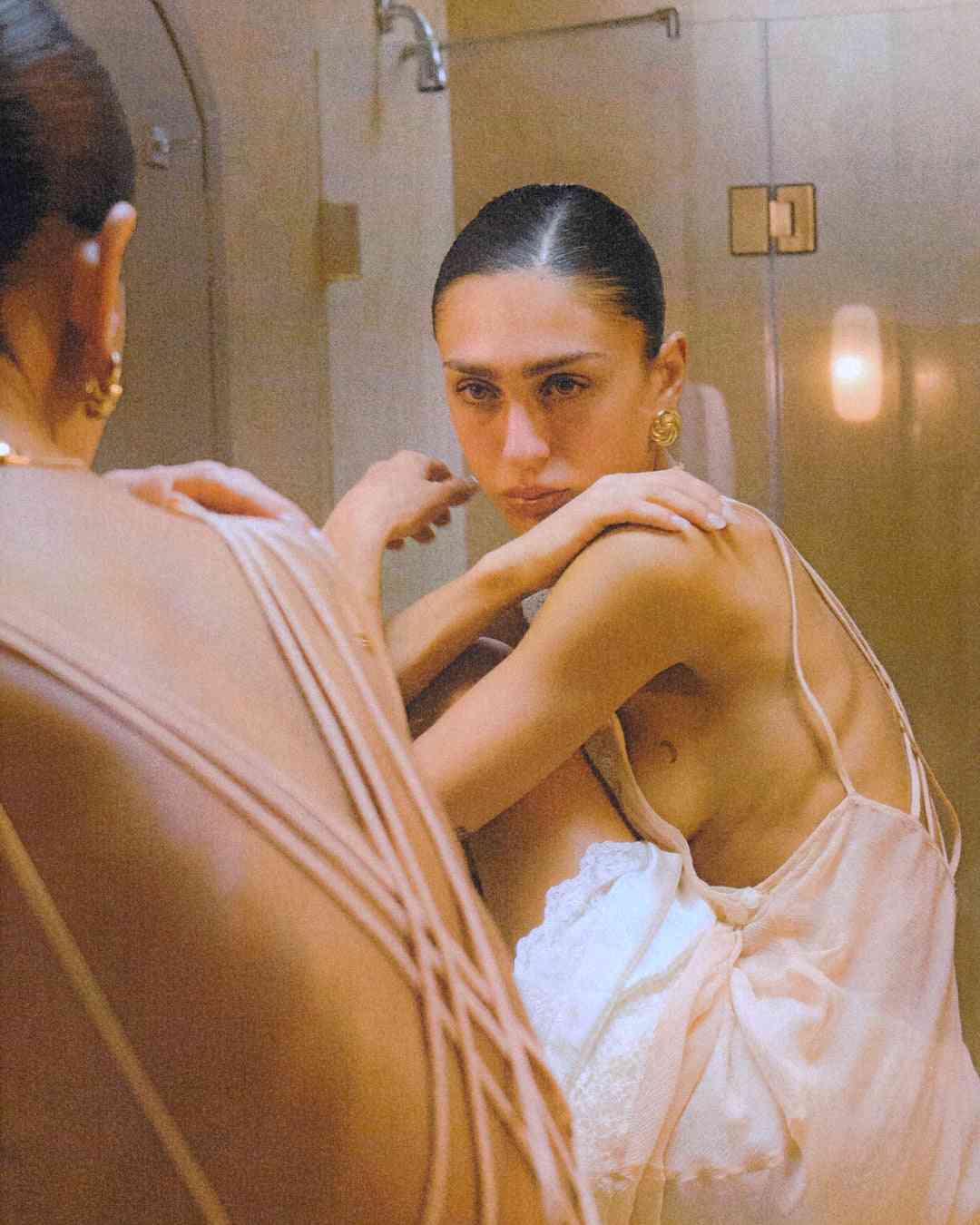 a woman in a bathrobe looking at her reflection in a mirror wearing Luv Aj The Leila Studs