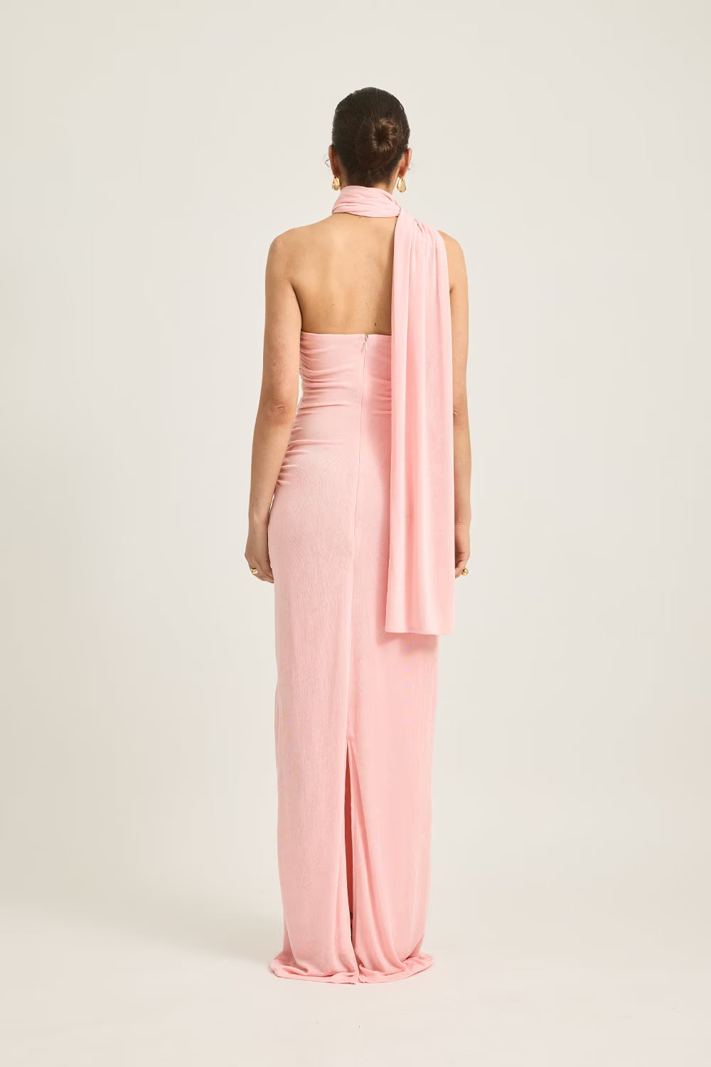 Iesha dress in soft pink, featuring a one-shoulder design and a flowing back scarf detail.