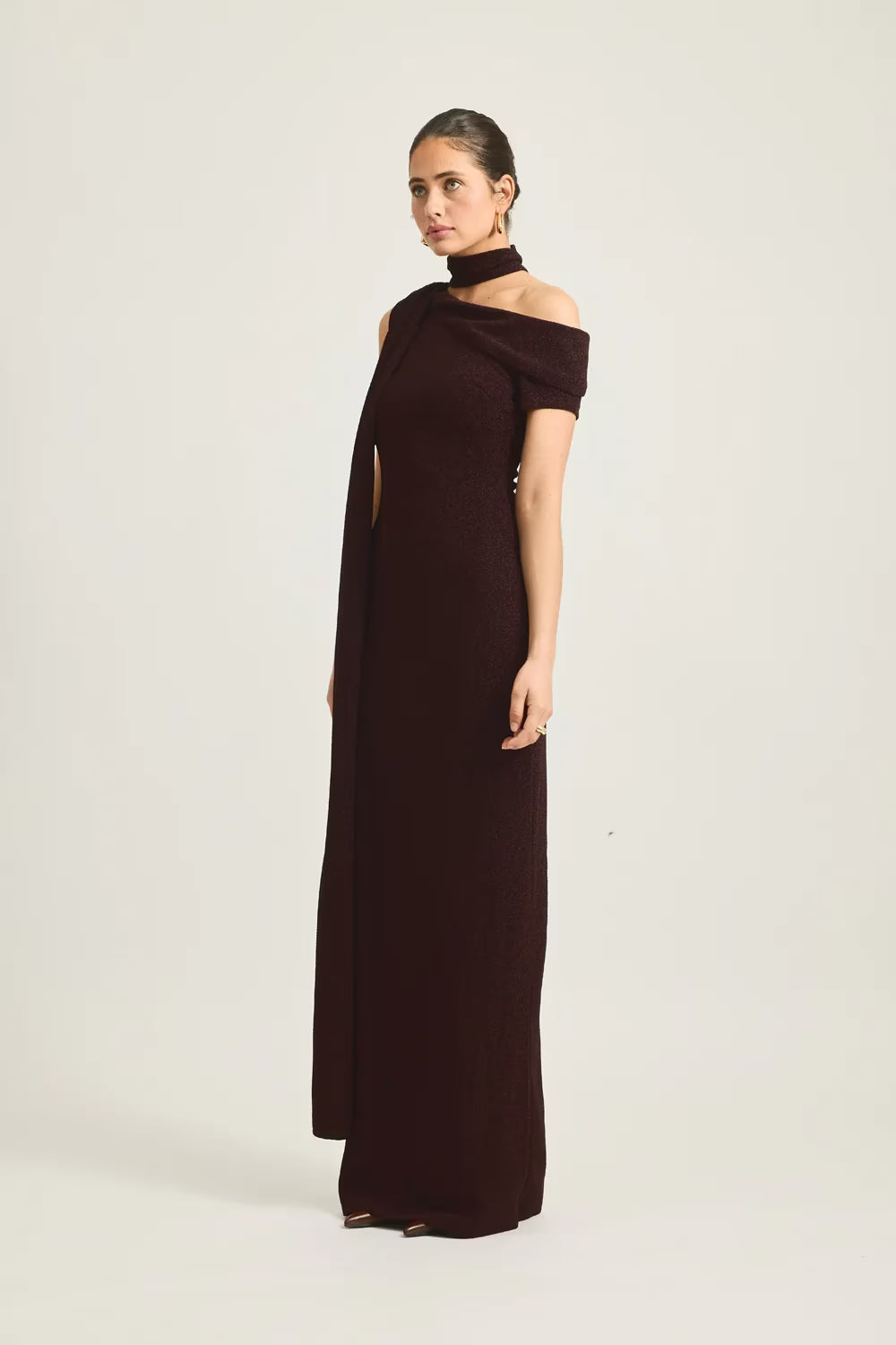 Izara dress in deep burgundy, featuring an off-shoulder design and a side slit, worn by a model against a neutral background.