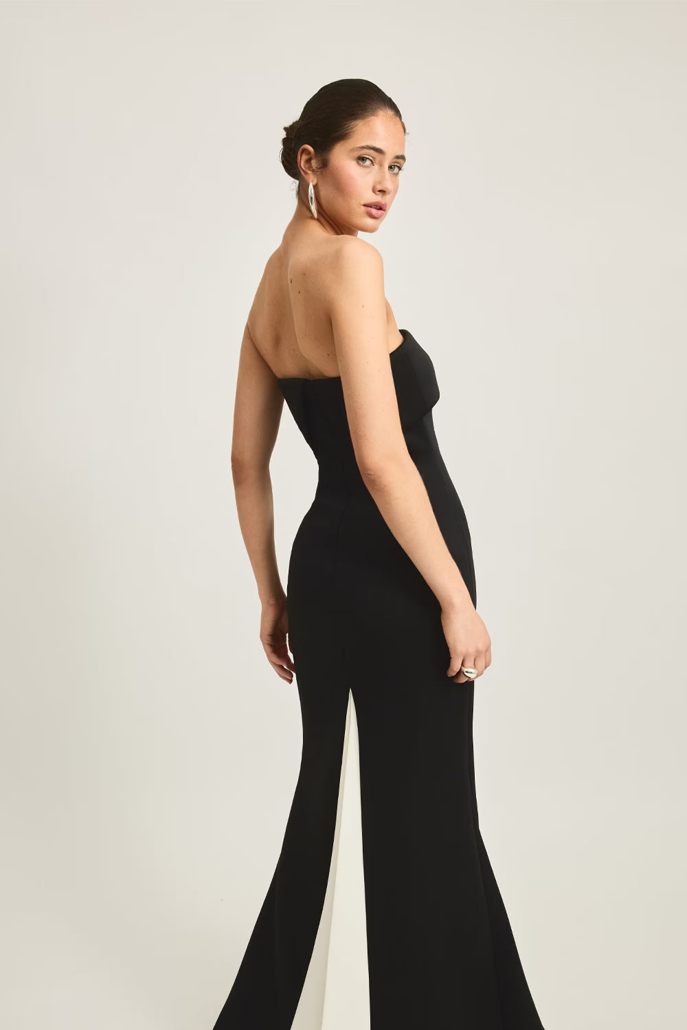 Stellan gown in black, featuring a strapless design and a fitted silhouette with a side slit, worn by a model.