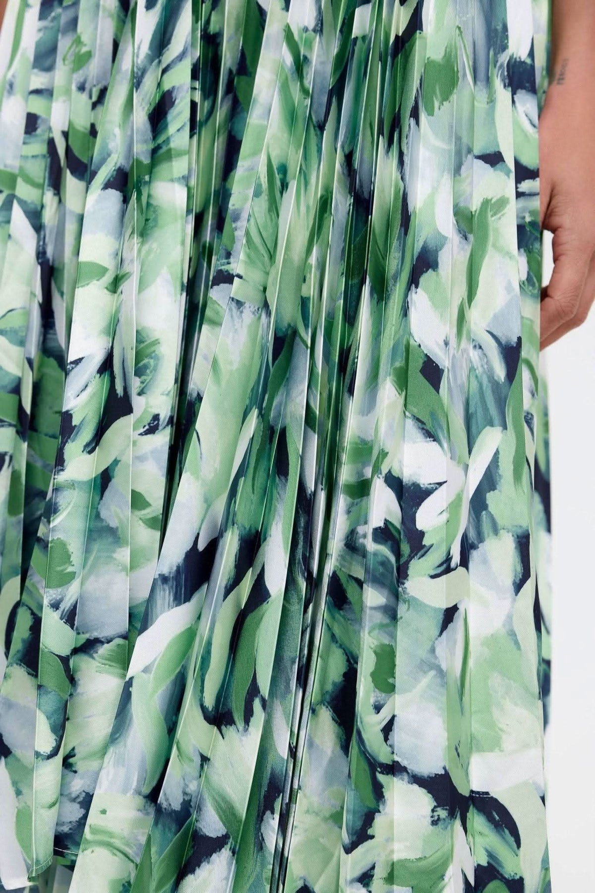 Close-up of green and blue leafy print pleated fabric on midi dress