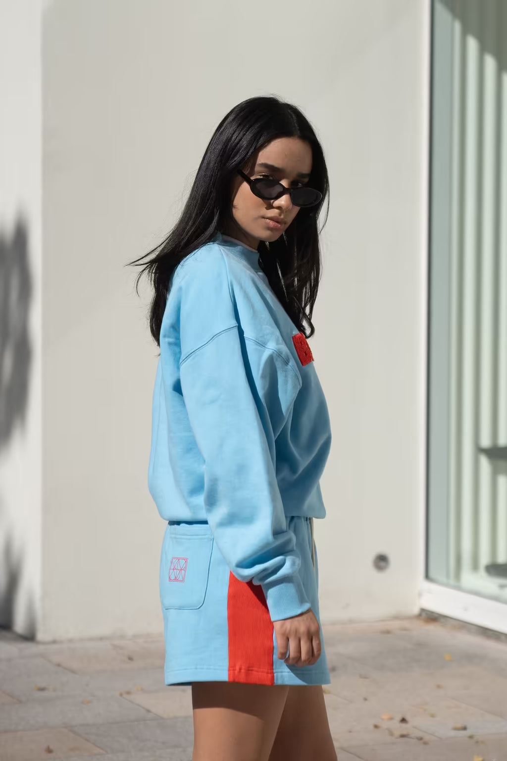 Ice blue track shorts with red side panel and small red logo patch