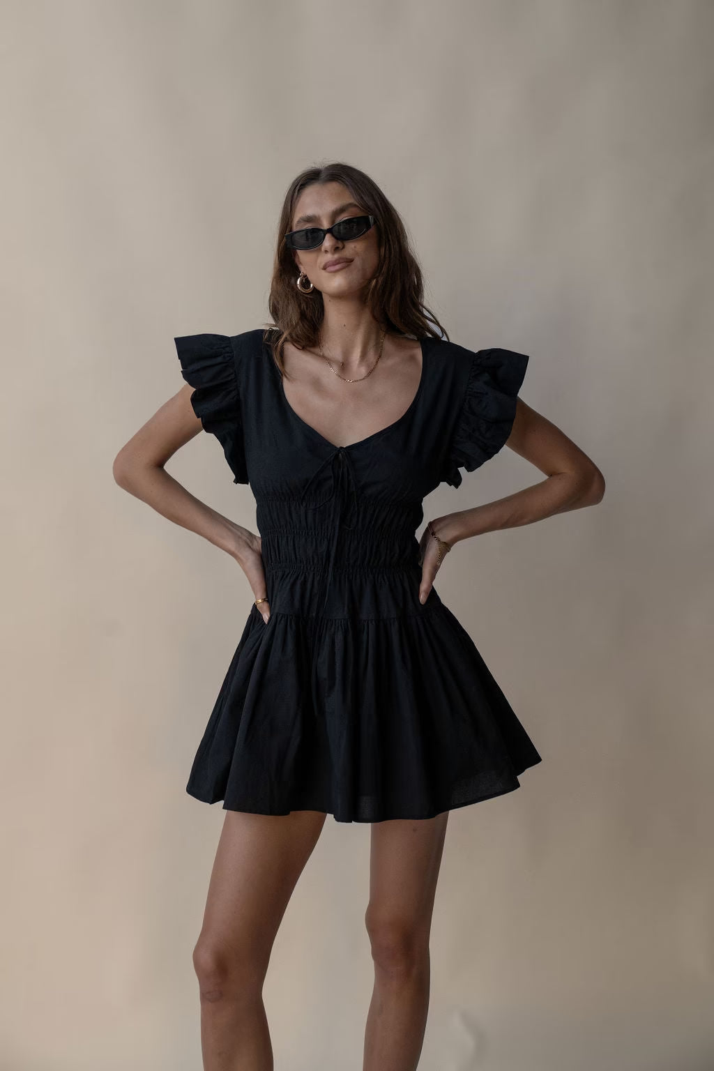 Black mini dress with flutter sleeves, ruched bodice, and gathered skirt