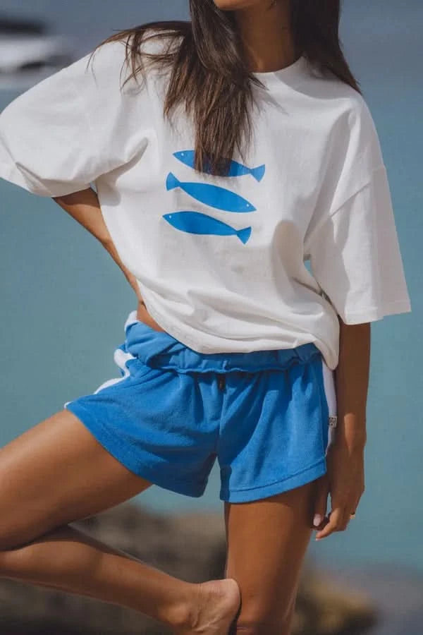 White crew-neck tee with blue fish graphic; short sleeves, relaxed drape.