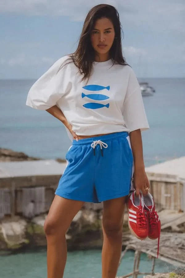 White crew-neck tee with blue fish graphic, short sleeves; worn over blue shorts.