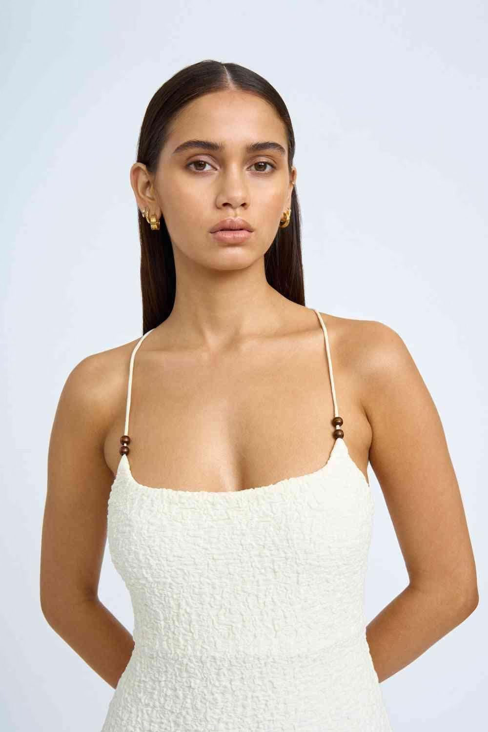 Ivory beaded midi dress close-up with thin spaghetti straps and textured bodice.