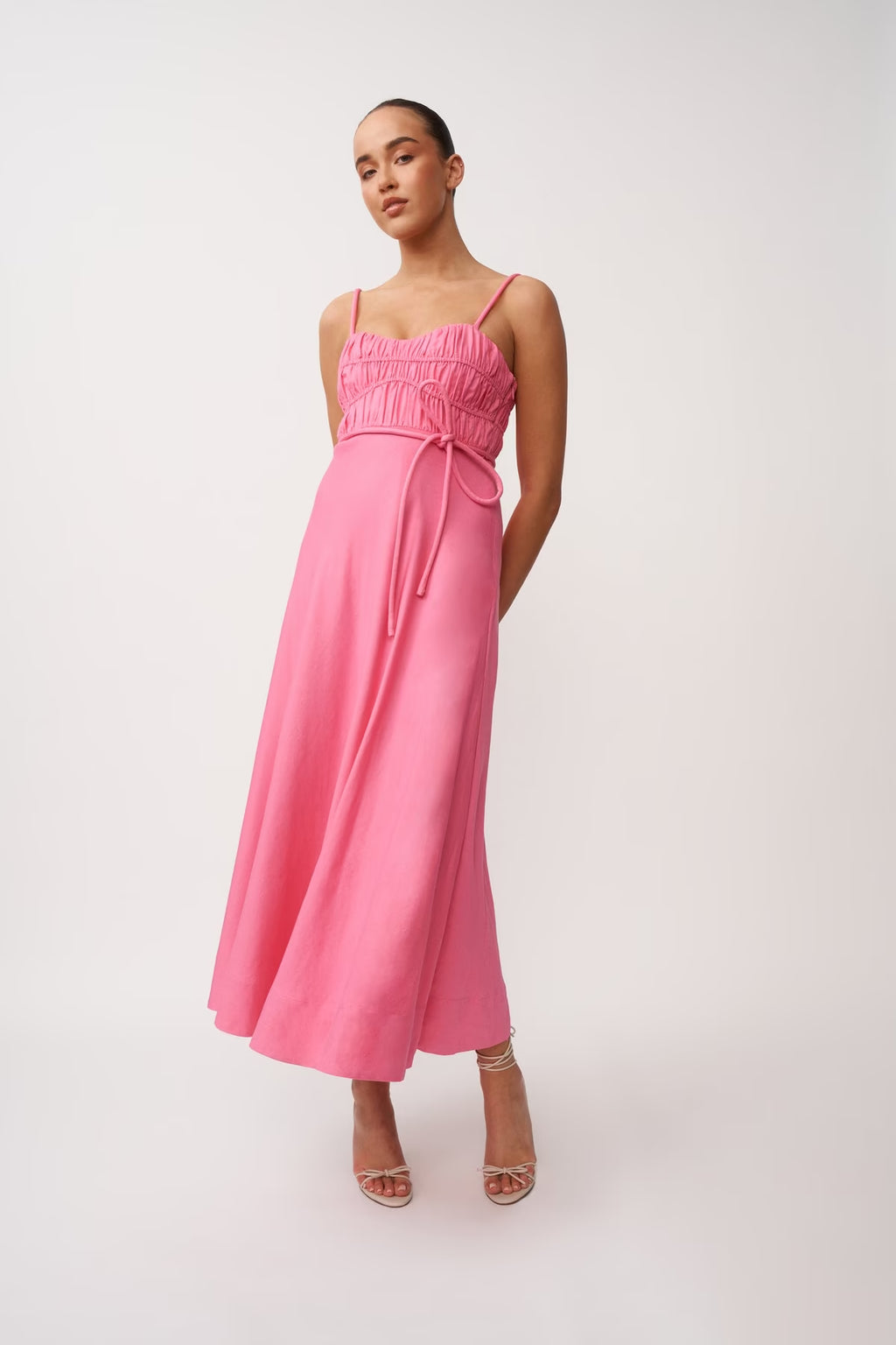 Pink midi panel dress with thin shoulder straps, ruched bodice, and drawstring waist tie.