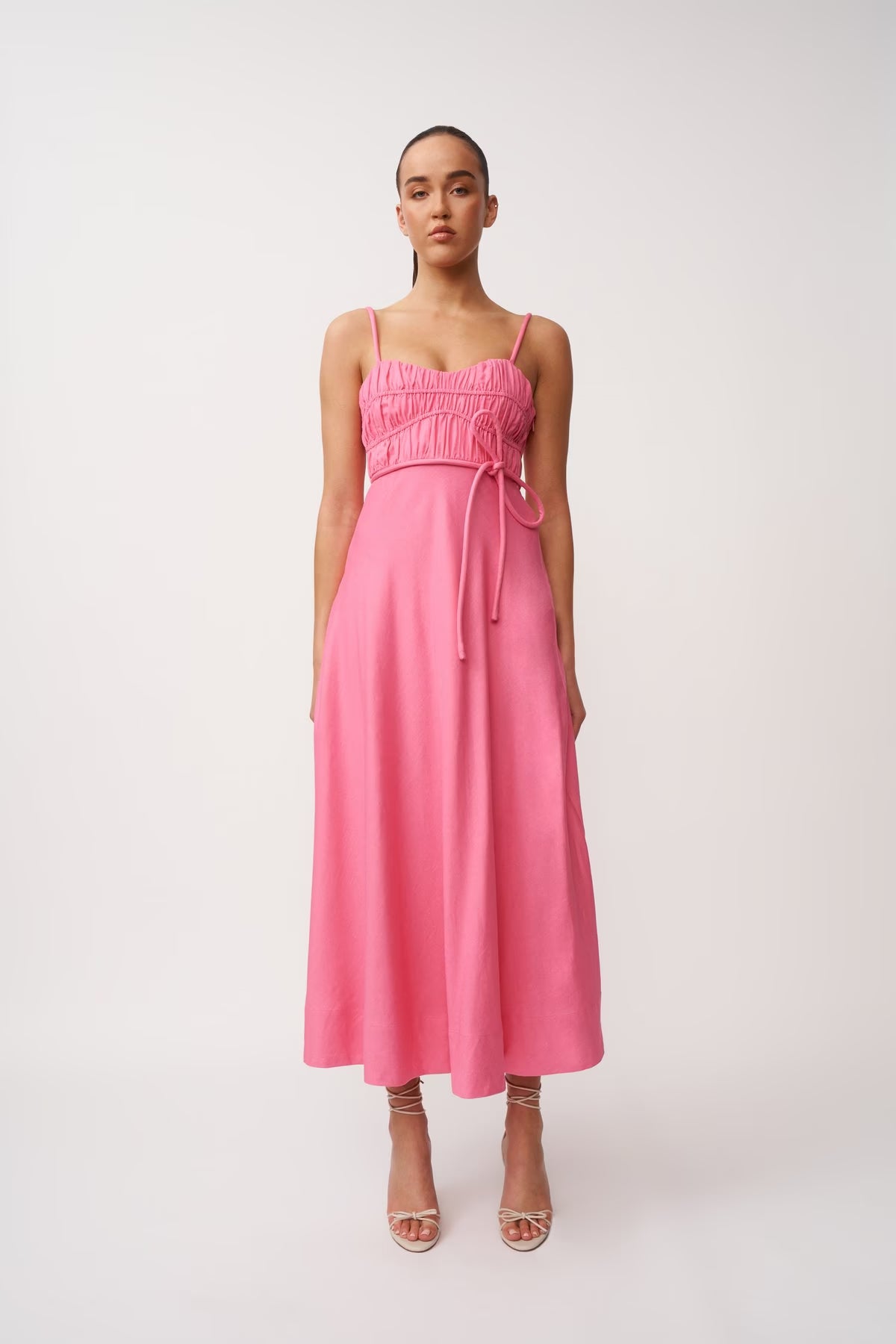 Pink midi panel dress, sleeveless with thin straps and gathered bust, tie belt at waist.