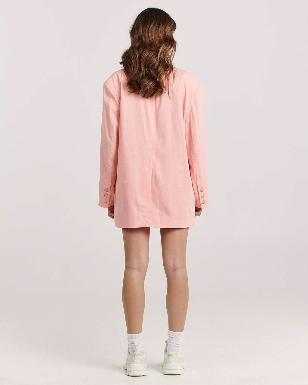 Back view of pink blazer with long sleeves and gold button details