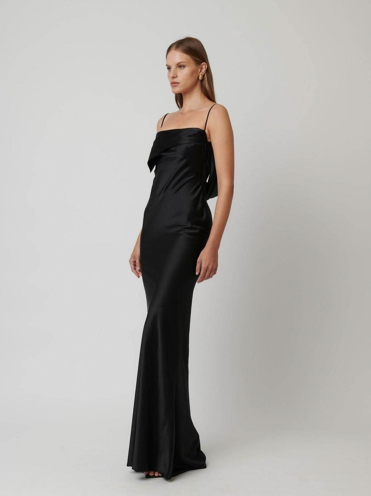 Black satin column gown with asymmetric straight neckline and thin spaghetti straps