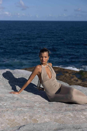 a woman sitting on top of a rock near the ocean in a Flook the Label Amoria Dress