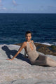 a woman sitting on top of a rock near the ocean in a Flook the Label Amoria Dress