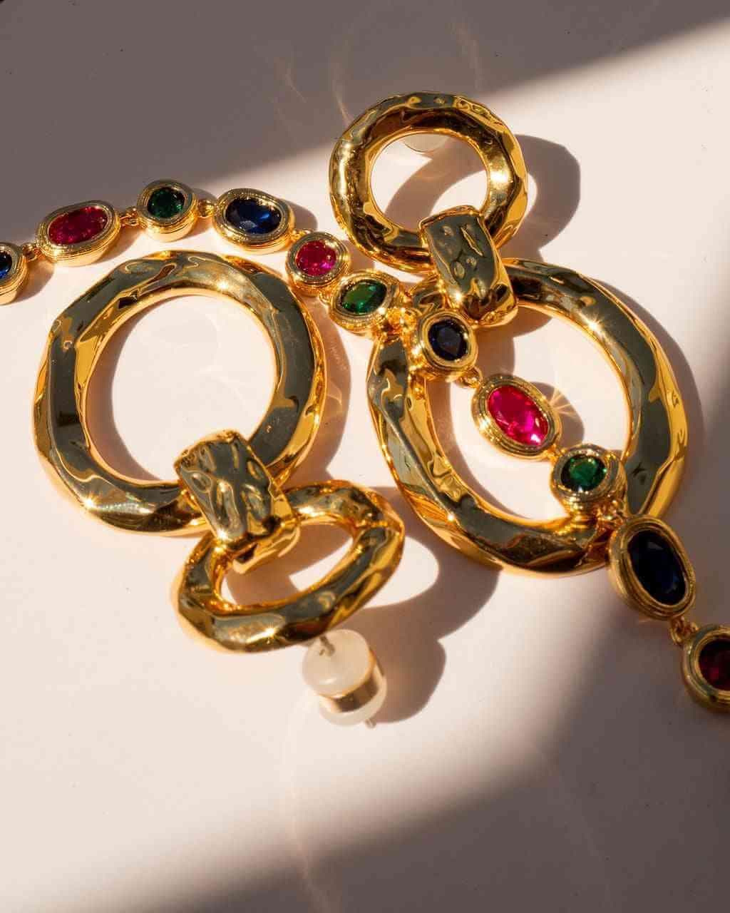 Gold hammered loop hoop earrings with round colored gemstone accents on layered rings
