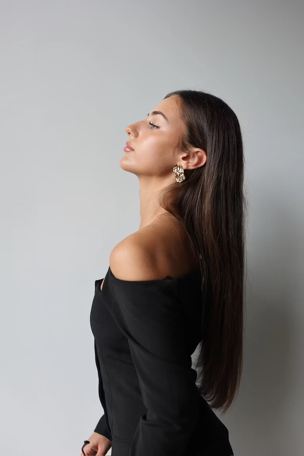 Gold textured square stud earrings worn by model in profile