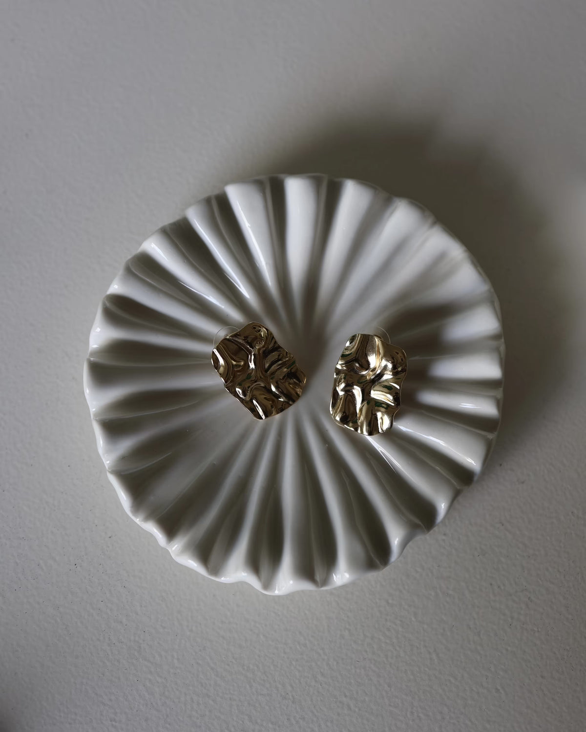 Gold textured square stud earrings shown centered with scalloped backing