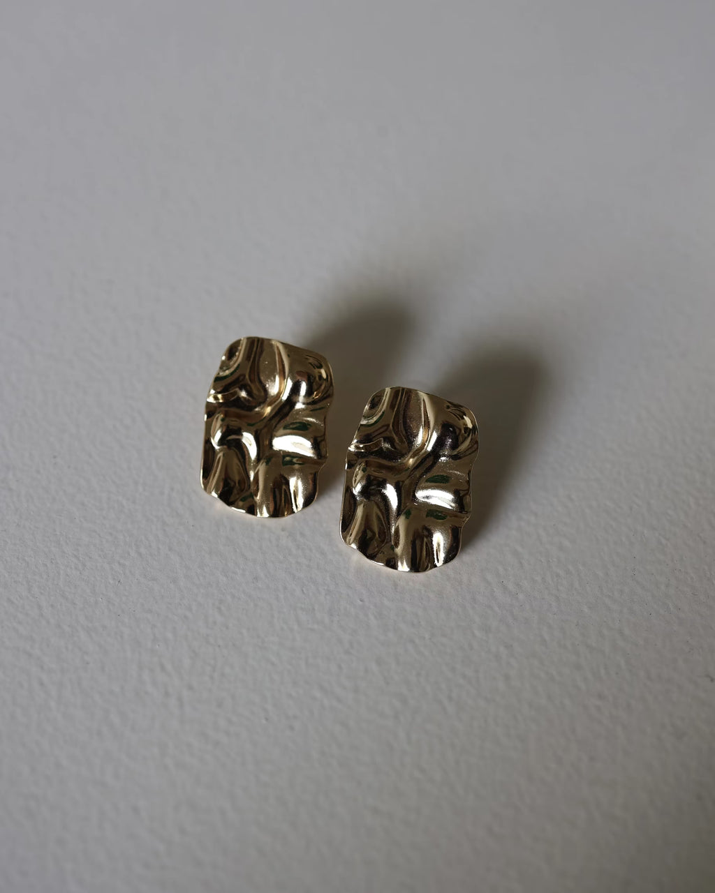 Close-up of gold textured square stud earrings