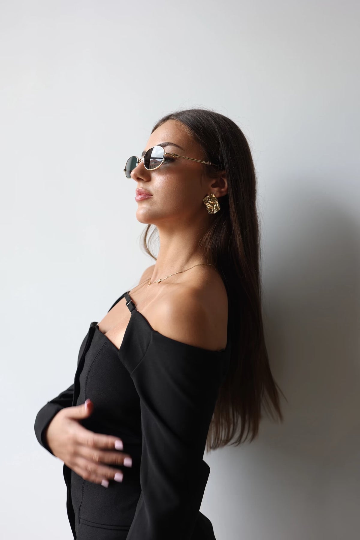 Gold textured square stud earrings worn by model, side profile view