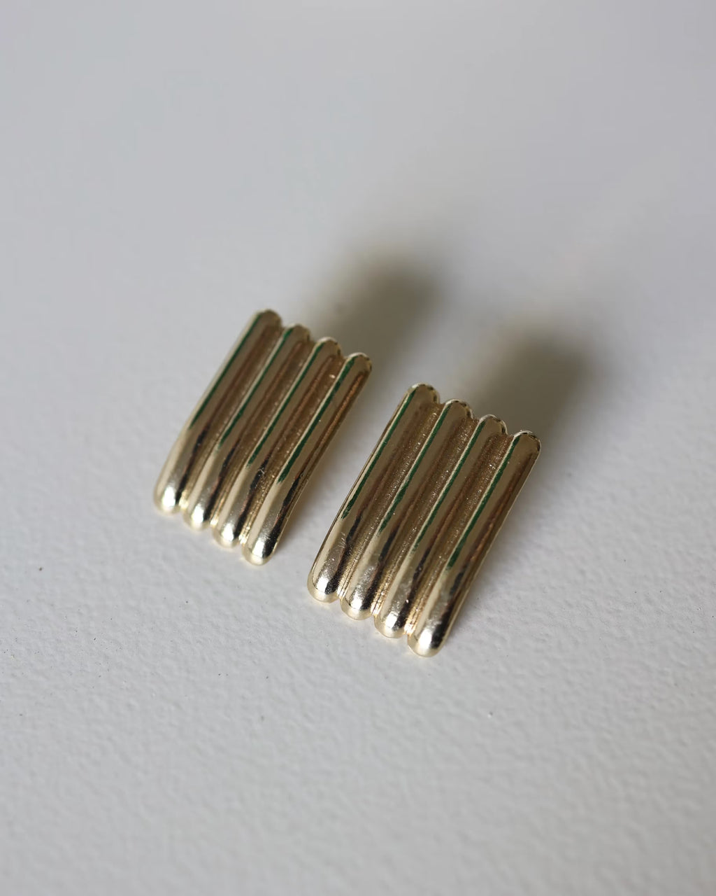Gold ridged half-hoop earrings with vertical grooves, angled pair