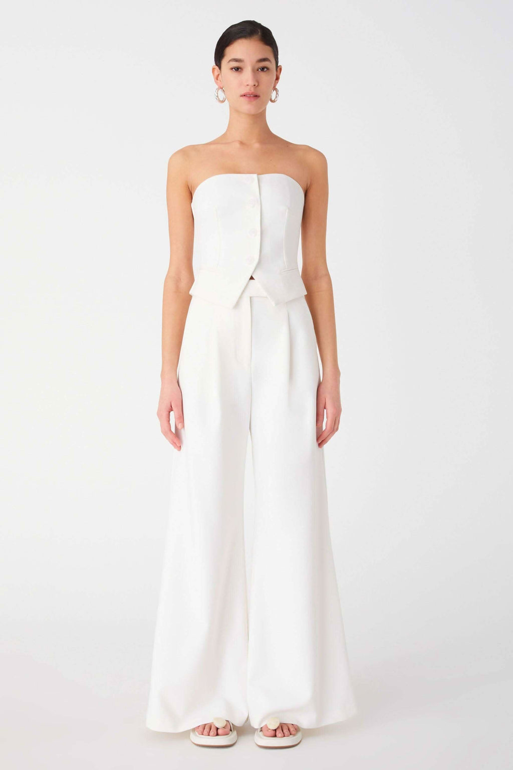 Ivory strapless top with structured bodice and peplum, paired with wide-leg trousers