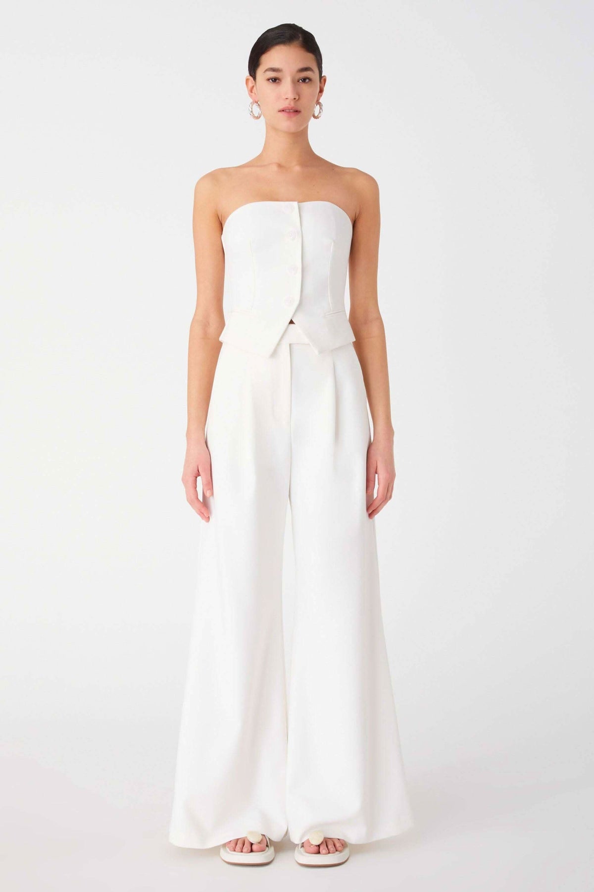 Ivory strapless top with structured bodice and peplum, paired with wide-leg trousers