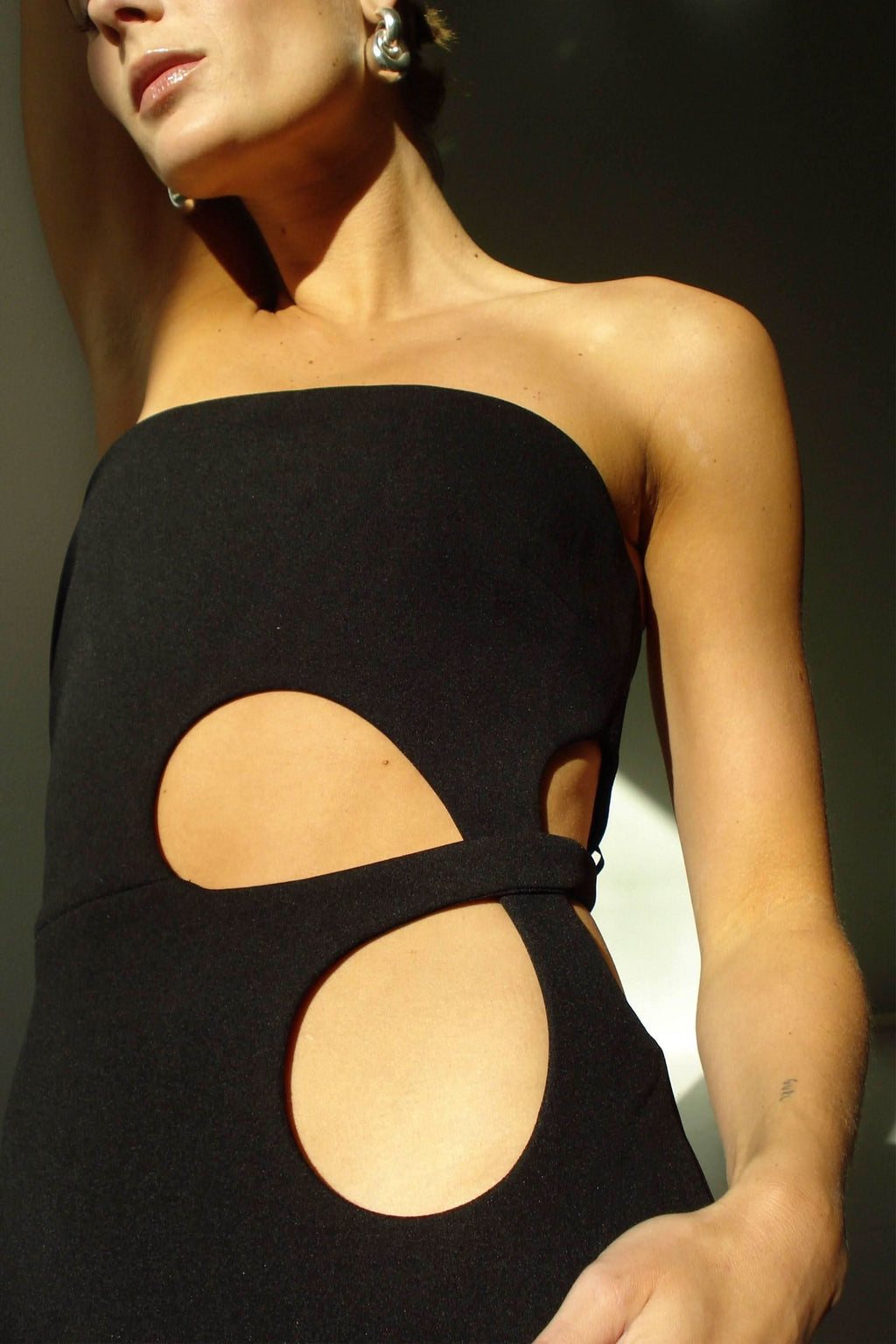 Black strapless midi dress close-up with circular cutouts on bodice