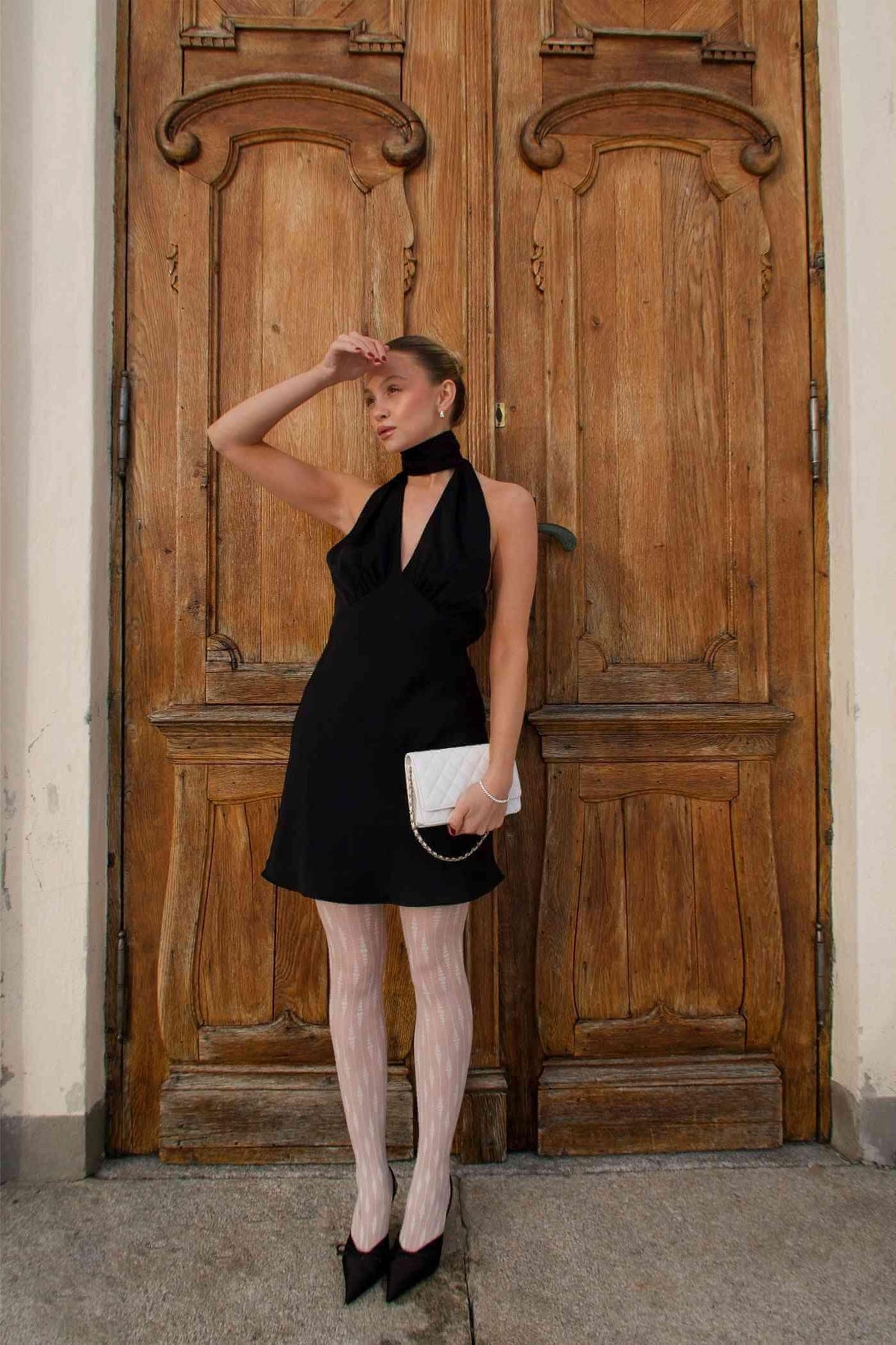 Black satin halter mini dress front view with open-back neckline and sleeveless silhouette