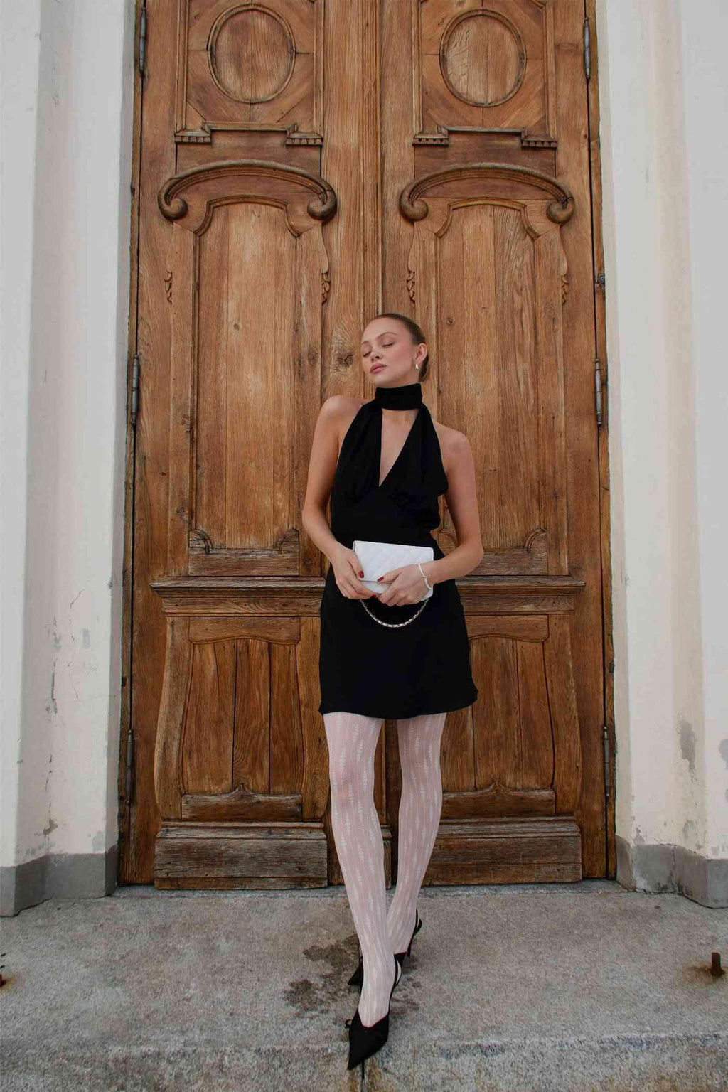 Black satin mini dress with halter neckline; open-back silhouette and short flared skirt