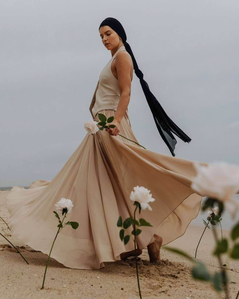 Stone sleeveless V-neck vest with button front, worn over a flowy layered skirt.