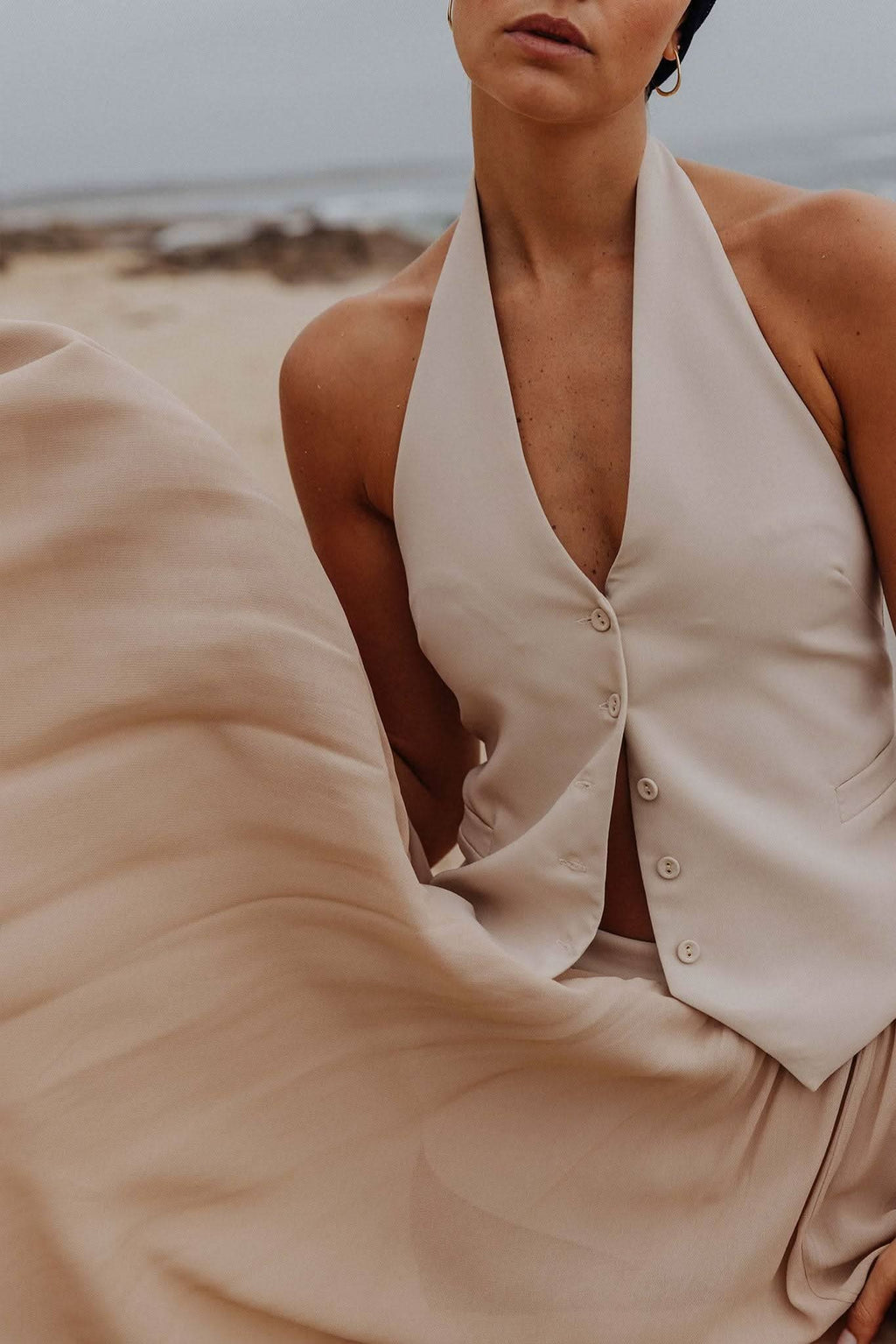 Stone halter vest close-up with button placket and soft V neckline, sleeveless