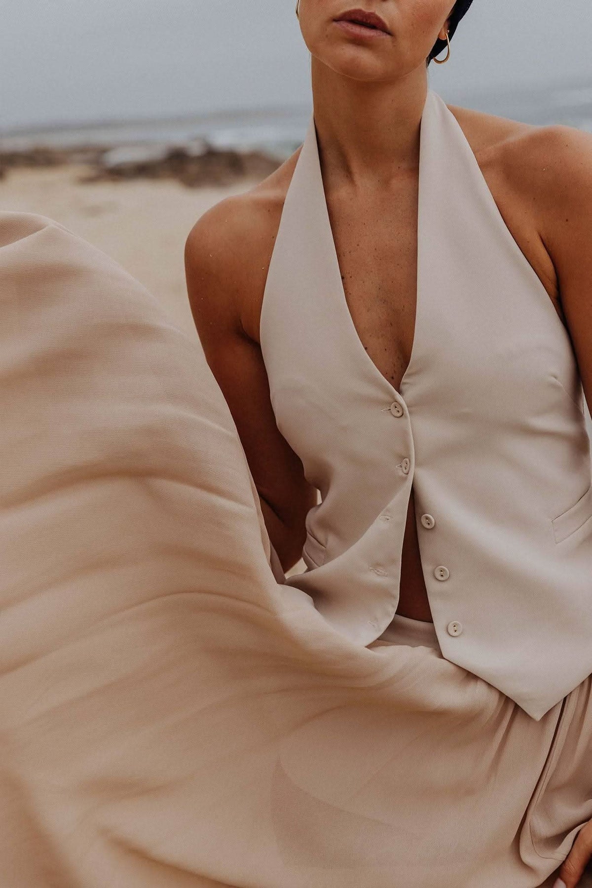 Stone halter vest close-up with button placket and soft V neckline, sleeveless