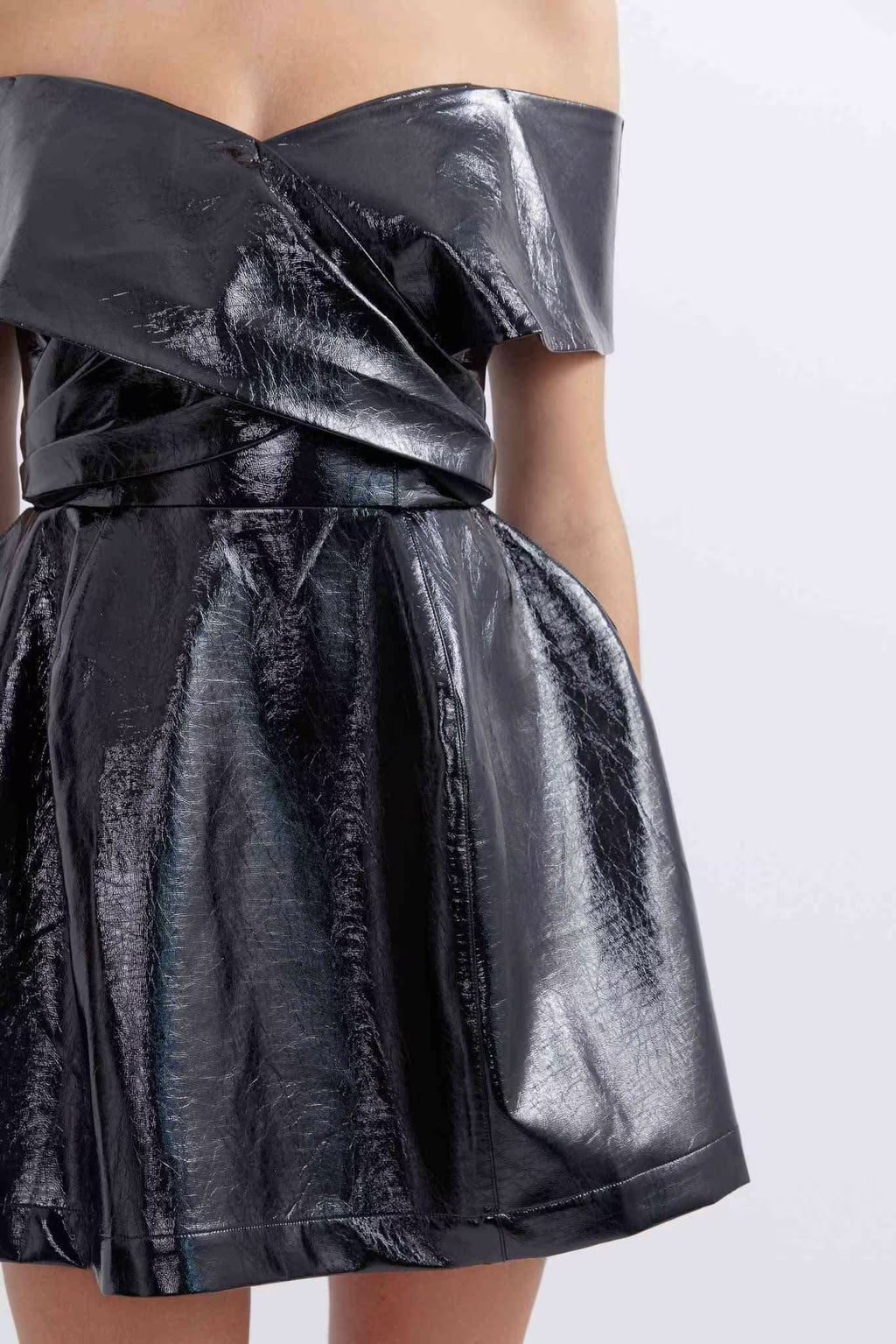 Close-up of black metallic off-shoulder dress with twisted waist bow and pleats