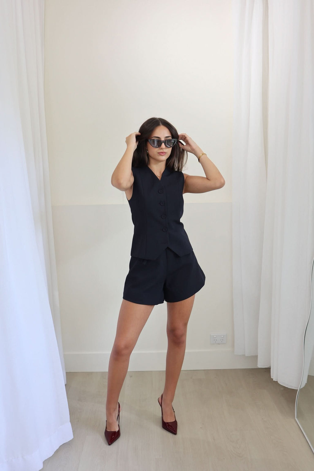 Navy sleeveless waistcoat with V-neck and button front, styled with matching shorts