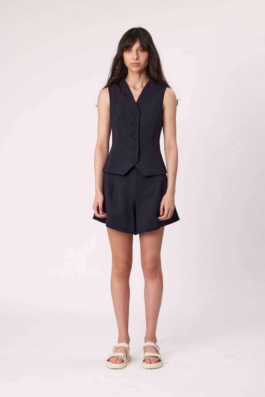 Navy sleeveless waistcoat with notch lapel and button front, paired with dark shorts