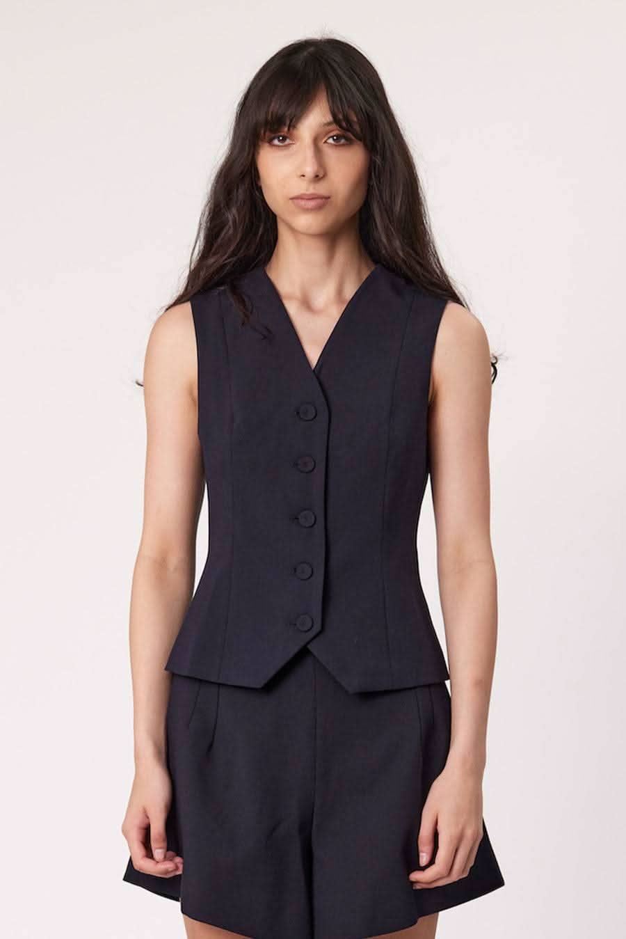 Navy sleeveless waistcoat with V-neck and four-button front, layered over shorts