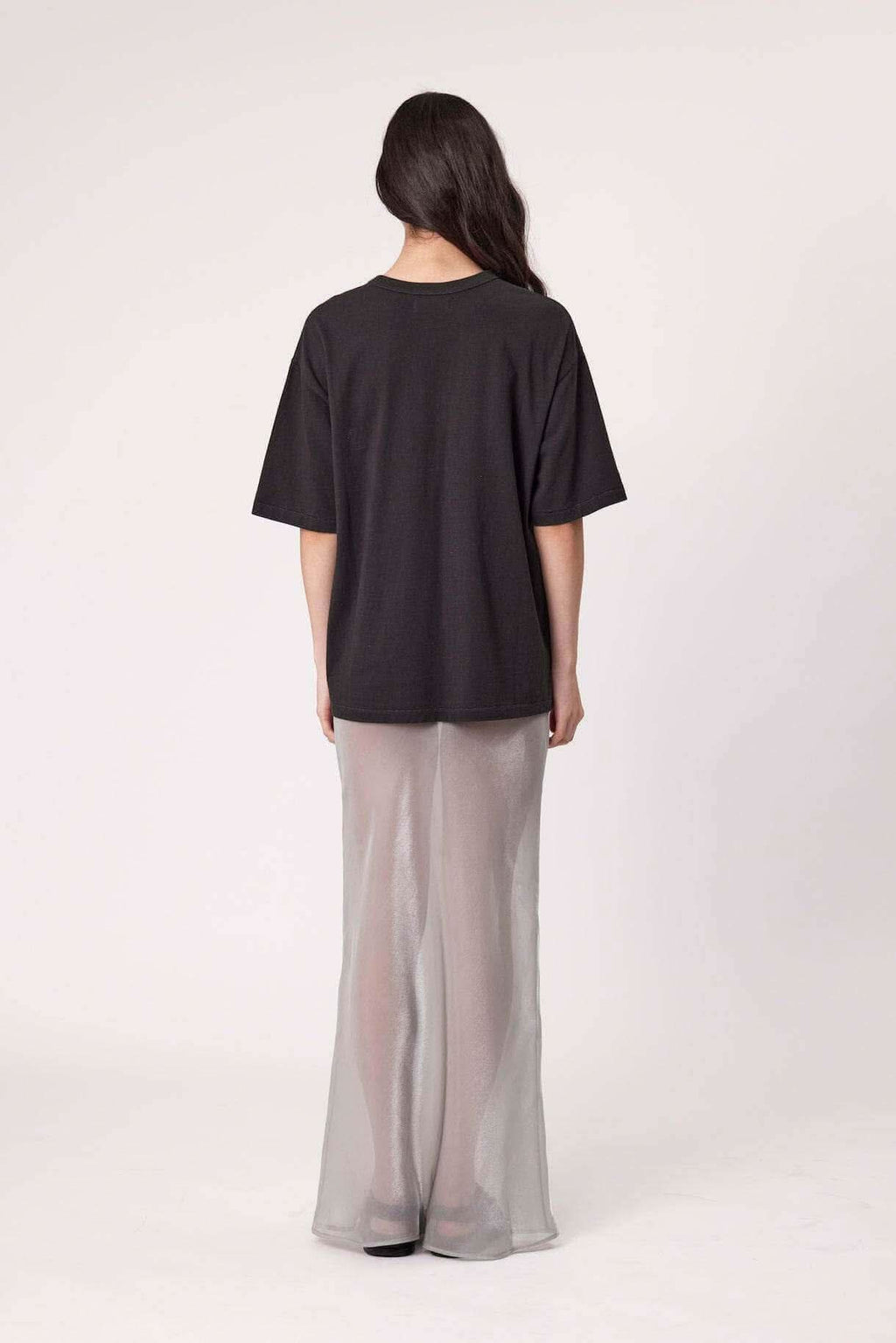 Washed black tee back view, plain short sleeves over light gray pants