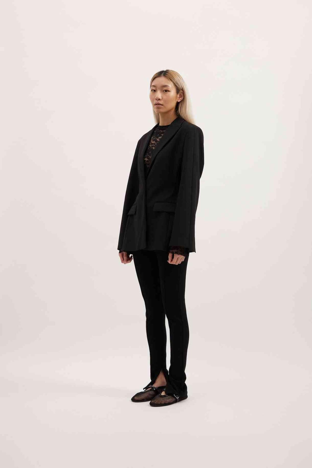 Black Sofia blazer in side profile with notch lapels and flap pockets