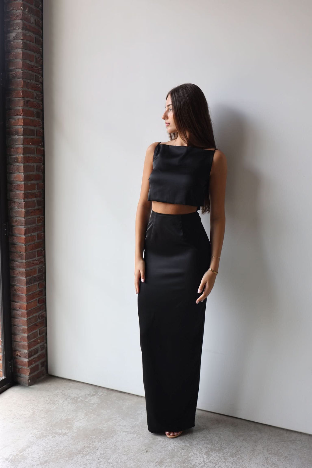 Black sleeveless crop-top gown with long column skirt, back-leaning side view