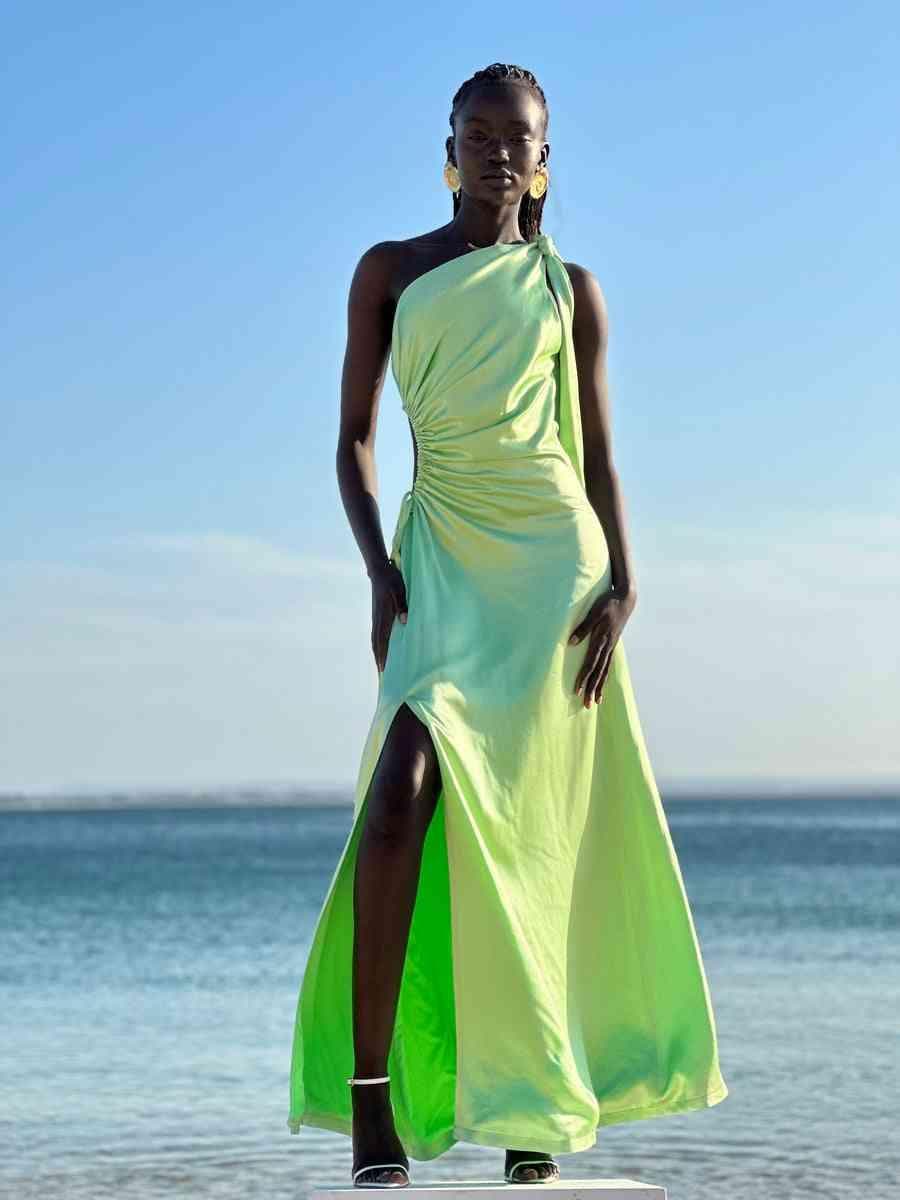 Light green one-shoulder halter maxi dress with high slit and draped side seam.